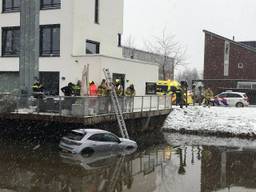 Auto belandt in het water, bestuurder wordt uit voertuig gehaald