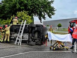 Bestelbus slaat om bij botsing op kruising, bestuurder bekneld