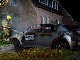 Elektrische auto in vlammen op, raam van huis springt door hitte