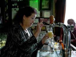 Hennie achter de bar bij haar café de Vredesduif (foto: studio040)