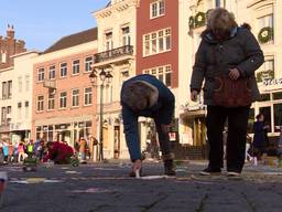 Volwassen mensen spelen met stoepkrijt op markt Den Bosch