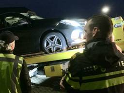 Agenten kijken toe hoe een auto wordt afgevoerd (foto: Belastingdienst).