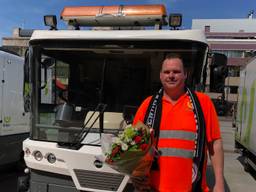 Een van de schoonmakers van ERGON met een bosje bloemen en PSV sjaal als dank