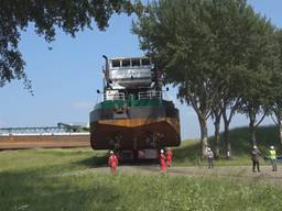 Baggerboot over land onderweg naar het water in het spaarbekken (foto Evides / Mediataal)