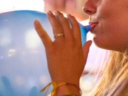 Een vrouw met een lachgasballon aan haar mond. (Foto: ANP)