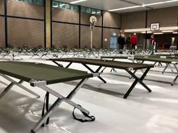 Vrijwilligers zetten maandag tientallen veldbedden in de gymzaal van scholengemeenschap 't Rijks. (Foto: Erik Peeters)
