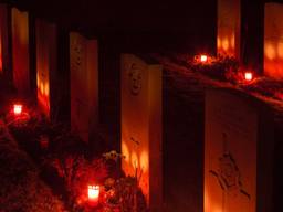 In het donker verlichten kaarsjes de oorlogsgraven in Overloon. (Foto: Albert Hendriks)