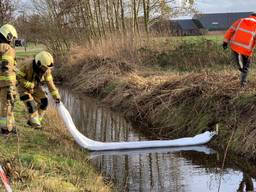 Brandweerlieden proberen met drijvende afzettingen te voorkomen dat de olie zich in de sloten verspreid. (Foto: Bart Meesters)