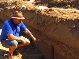 Archeoloog Nico van der Feest laat stukjes van de weg zien. 