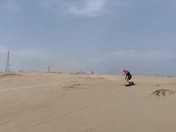 Brandweermannen snowboarden door de Peruaanse duinen.