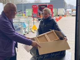 Een vrouw brengt een doos tweedehands spullen naar de kringloop in Schijndel