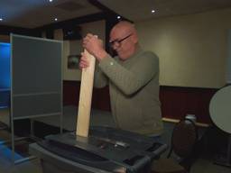 Met een lange plank en grof geweld stamt Rene de stembiljetten aan (beeld: Omroep Brabant).