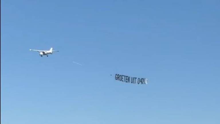 Een reclamevliegtuig met 'Groeten uit 040' vliegt over Amsterdam.