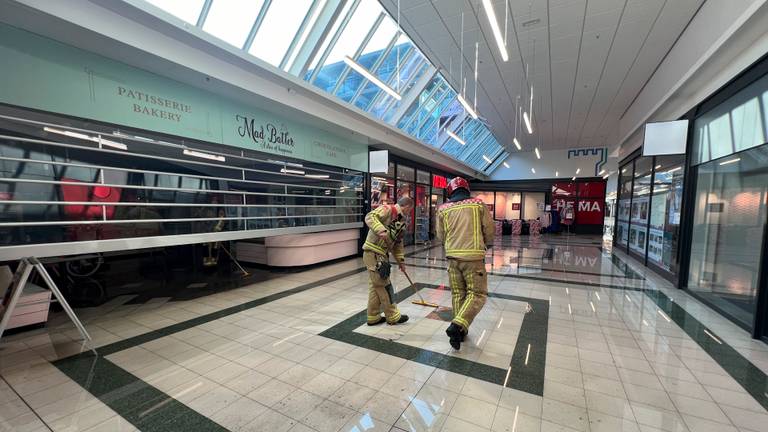 Brandweerlieden werken het water weg nadat sprinklerinstallaties in een winkelcentrum waren afgegaan (foto: SQ Vision).