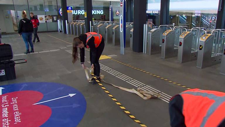 Op het station in Eindhoven worden coronastickers geplakt.