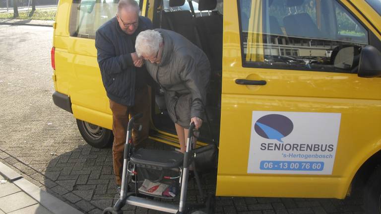 Een vrijwilliger van de Bossche Seniorenbus helpt een passagier uitstappen (foto: Seniorenbus Den Bosch)
