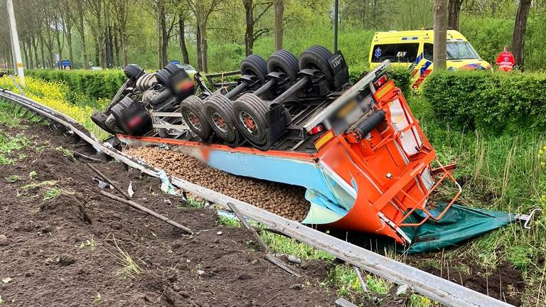 Vrachtwagen met aardappelen kantelt en belandt naast de snelweg