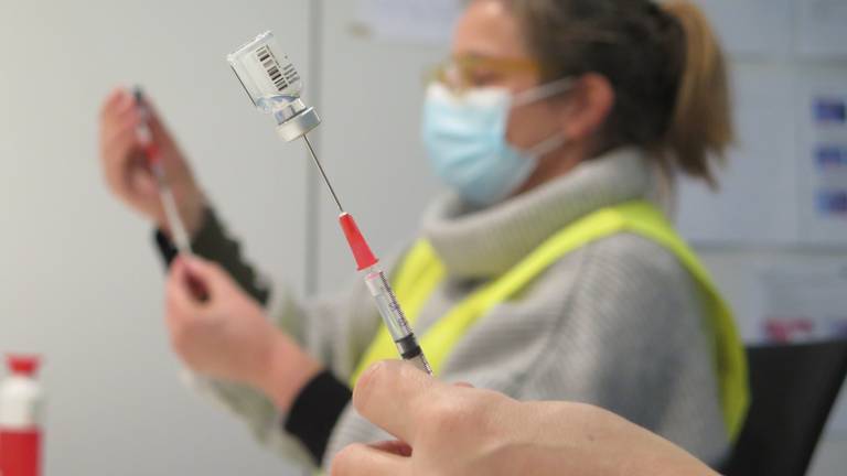 Achter de schermen zuigen GGD-medewerkers het coronavaccin met spuiten uit de flacons (foto: Joris van Duin).