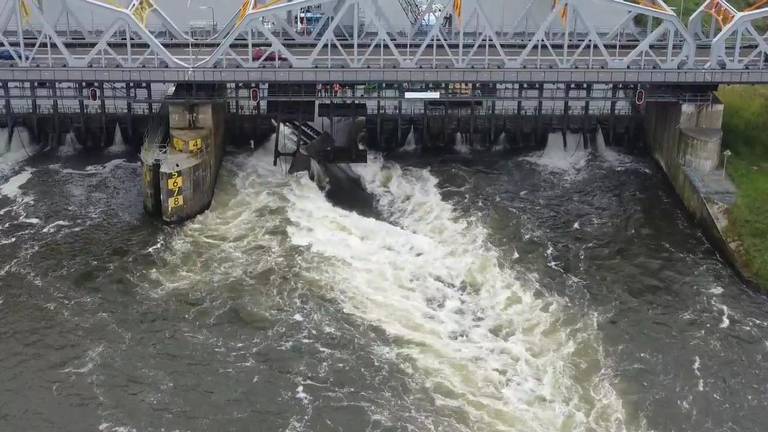 Water perst zich door de stuw bij Grave.