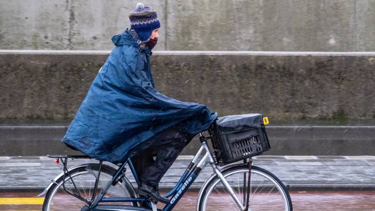 Een fietser rijdend door de natte sneeuw (foto: ANP 2021/Egbert Hartman).