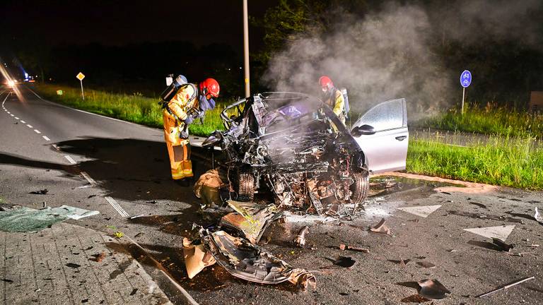 Ravage op de weg na botsing auto met vrachtwagen, auto vat vlam