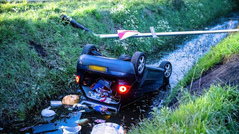De auto kwam na de crash ondersteboven in de sloot naast de Zuiderkruisweg in Tilburg terecht (foto: Jack Brekelmans/.SQ Vision).