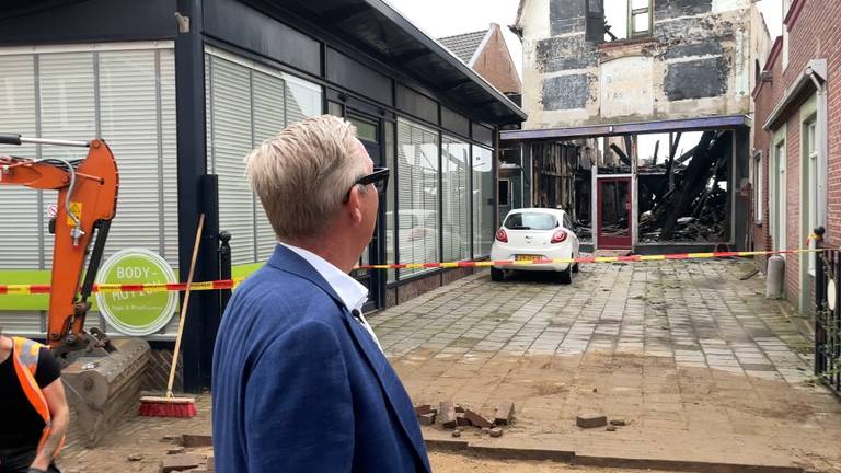 Martijn Jansen bekijkt de ochtend na de brand het uitgebrande pand vlak naast zijn zaak.