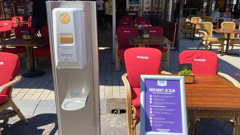 Desinfectiemiddel en huisregels staan duidelijk zichtbaar opgesteld op het terras bij café Slagroom in Tilburg.
