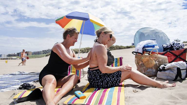 Badgasten op het strand smeren zich in met zonnebrandcrème (foto: ANP). 