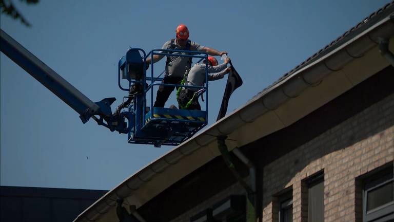Met een hoogwerker wordt een dak aan de Biezenloop gerepareerd.