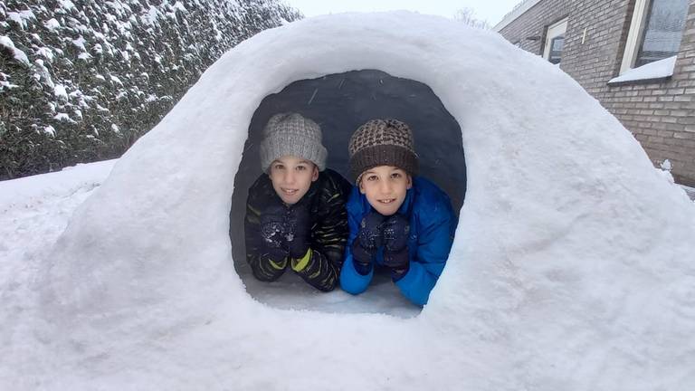 De vrolijke tweeling Teun en Rens trots op hun zelfgemaakte iglo in Lieshout (foto: Jolanda van den Dungen).