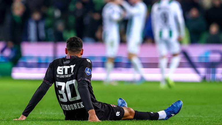 Raffael Behounek van Willem II is er na de nederlaag bij gaan zitten, terwijl Groningen-spelers een feestje vieren (foto: Orange Pictures).