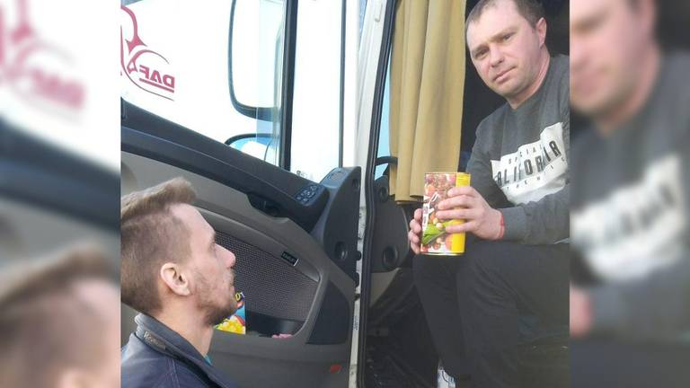 Robin geeft een blik soep uit aan een Oekraïense vrachtwagenchauffeur.