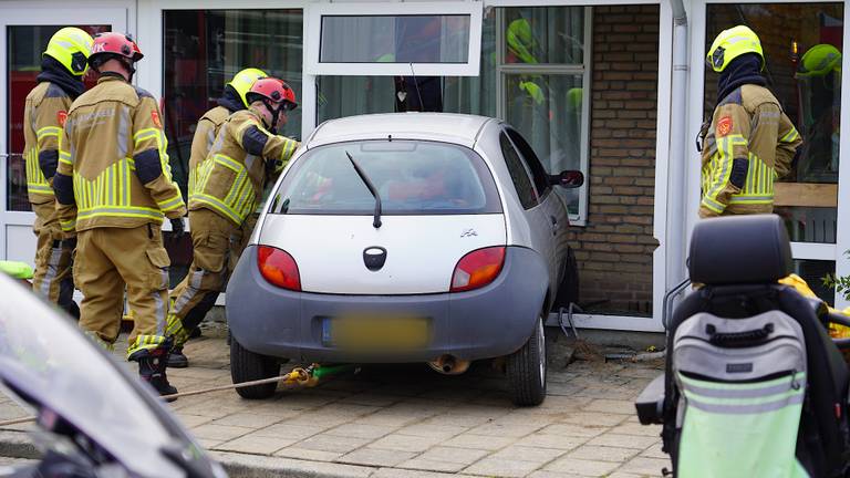 Oudere vrouw rijdt met auto gebouw binnen, brandweer bevrijdt inzittenden