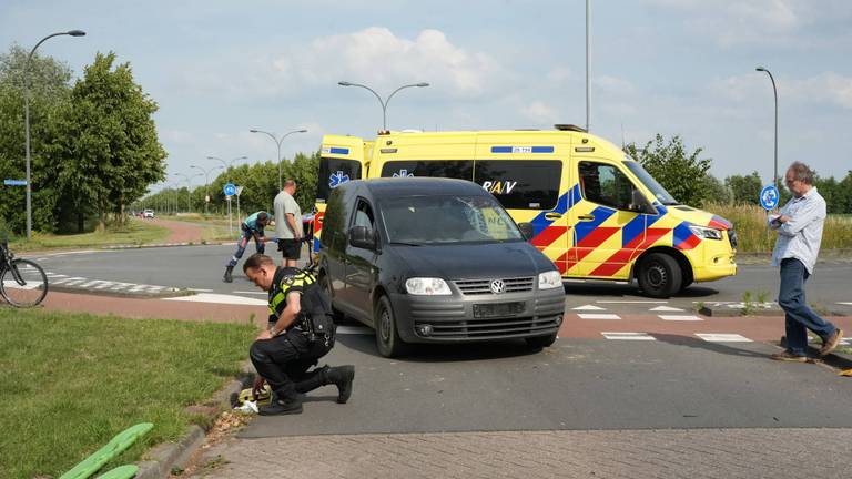 Auto schept fietser op rotonde