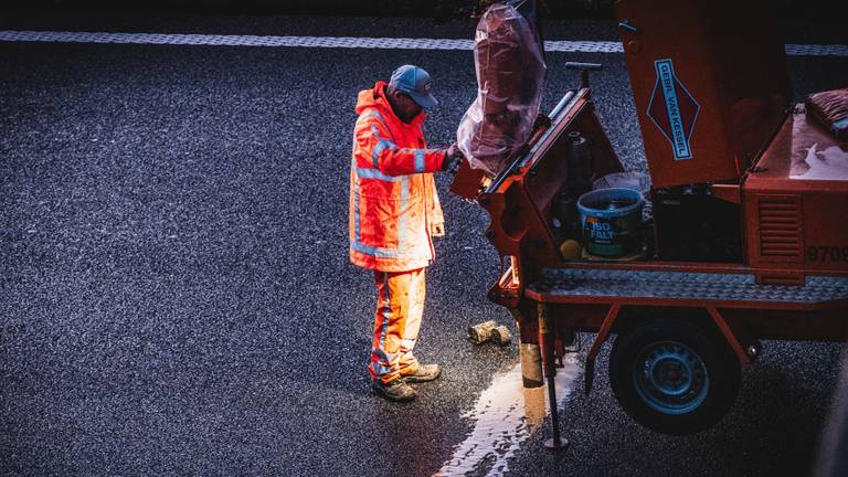 Een wegwerker vernieuwd het wegdek op de A58 bij Breda (foto: ANP).