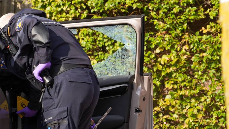 Politie bij een beschadigde auto na een schietpartij in de Klaverhof (foto: Harrie Grijseels/Persbureau Heitink).
