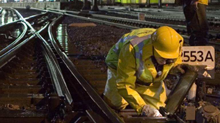 Een medewerker van Strukton aan het werk aan het spoor