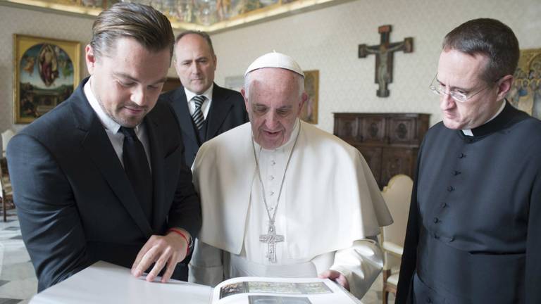 Leonardo DiCaprio bladert met de paus door het boek. (Foto: ANP)