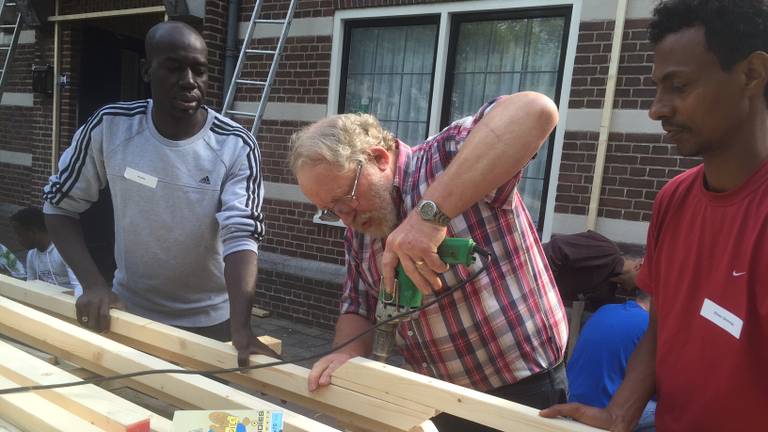 Vluchtelingen en vrijwilligers pakken samen het raadhuis in (foto: Tonnie Vossen)