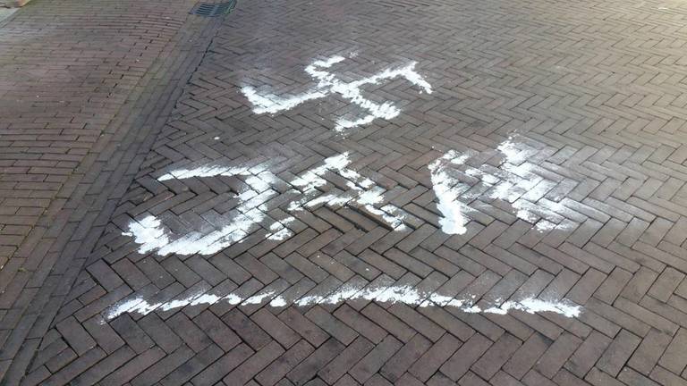 Hangjongeren tekenen een hakenkruis op straat. (Foto: Bas Douze/Twitter)