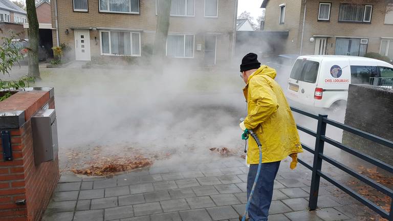 Willy Looymans spuit de stoep schoon bij De Vonder. (Foto: Noel van Hooft)