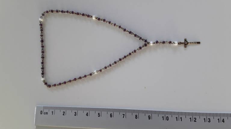 Wie is de standhoudster die deze rozenkrans te koop aanbood?