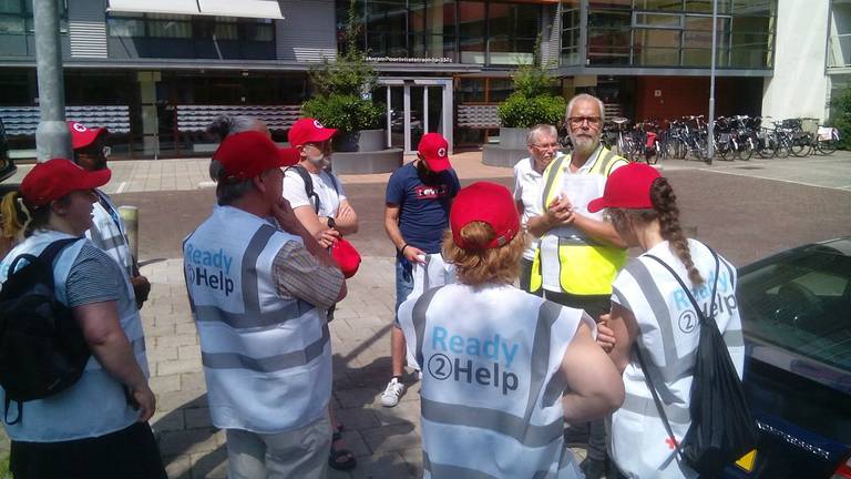 De helpers trotseren de warmte om senioren een glaasje water aan te bieden. (Foto: Twitter @Ready2Help_NL)