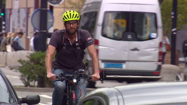 Het is een apart straatbeeld: een fietser tussen de auto's en vrachtwagens.