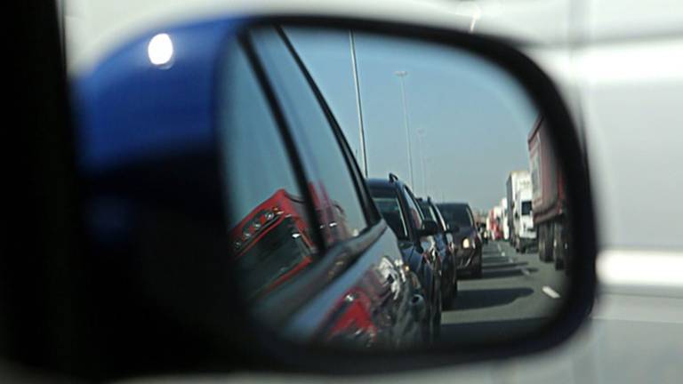 Een file gezien vanuit een zijspiegel van een auto.