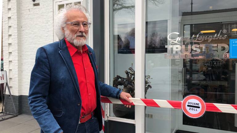 Kapper Maarten Ploegmakers bij de ludieke grensovergang voor zijn salon in Schaijk