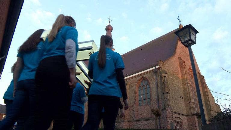 Kinderen dragen een kruis naar de kerk