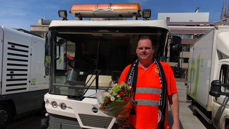 Een van de schoonmakers van ERGON met een bosje bloemen en PSV sjaal als dank