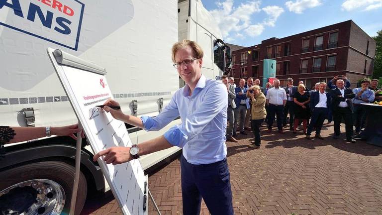 Gedeputeerde Christophe van der Maat tekent de overeenkomst “Vrachtwagenparkeren in West-Brabant”.